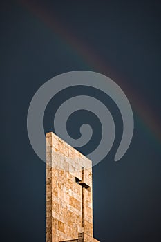 A rainbow above a modern church tower with christian cross, image with copy-space