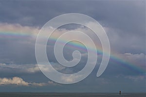 Rainbow above the north sea against a blue sky with clouds