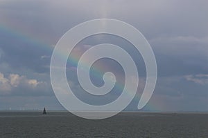 Rainbow above the north sea against a blue sky with clouds