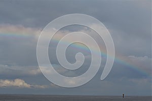 Rainbow above the north sea against a blue sky with clouds