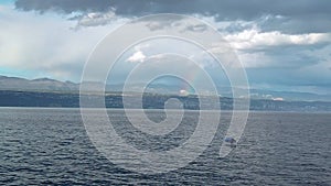 Rainbow above small fishing boat in thunderstorm