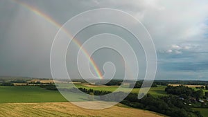 Rainbow Above Wheat Field.  Ripe Crop Field After Rain and Colorfull Rainbow in Background Rural Countryside. Aereal Dron Shoot.