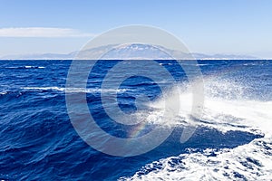 A rainbow appears in the bow wave of the boat during a trip on the sea around the island of Zakynthos, Greece