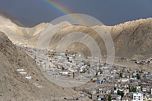 Rainbow appears in the dark sky before the rain falls in Leh town.