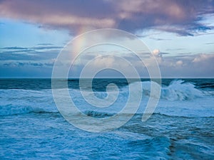 a rainbow appears in the sky above the ocean and beach