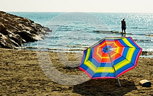 Rainbow beach umbrella on sand on the background of warm Mediterranean Sea in Cyprus Larnaca in summer