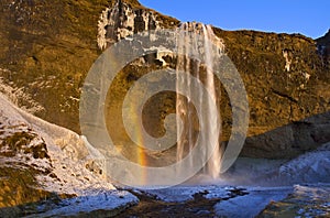 Rainbow caught in the mist and evening light, Seljalandsfoss Waterfall, Iceland