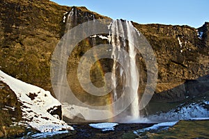 Rainbow caught in the mist and evening light, Seljalandsfoss Waterfall, Iceland