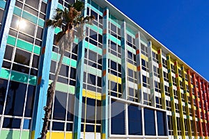 Rainbow cheerful office / residential building with windows. The facade of the house with a palm tree against blue sky in Israel
