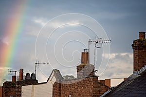 Rainbow over rooftops with storm clouds in background
