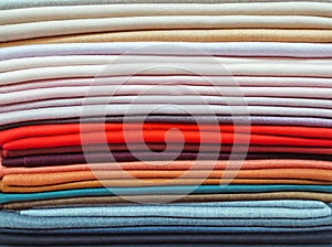 Rainbow clothes background. Pile of bright folded clothes