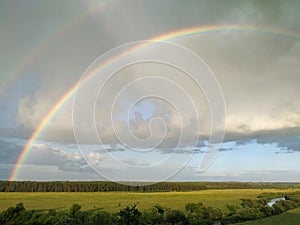 Rainbow and clouds over fields and river, smart