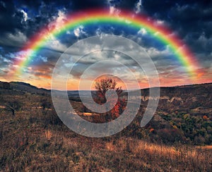 Rainbow with clouds over a rock