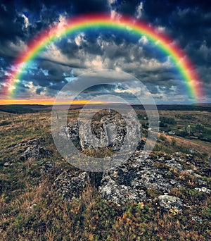 Rainbow with clouds over a rock