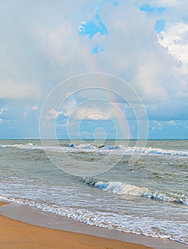 Rainbow in the cloudy sky over the sea - view from the beach