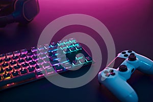 Rainbow color backlighted gaming keyboard, controller and stereo headphones. Purple light from top