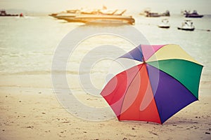 Rainbow color umbrella on beach. Holiday and Forgotten Object co