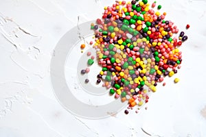 Rainbow colored candy sprinkled on a white background