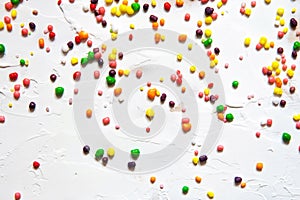 Rainbow colored candy sprinkled on a white background