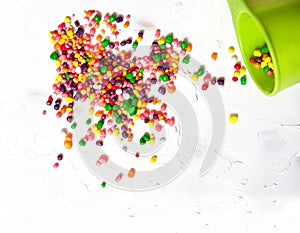 Rainbow colored candy sprinkled on a white background