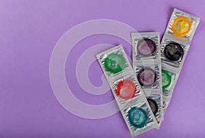Rainbow of colored condoms on background.