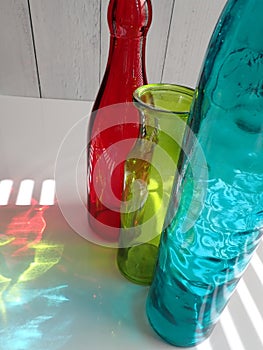 Rainbow colored glass vases, through sun glare in window