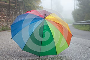 Rainbow colored umbrella on the street on rainy day in autumn