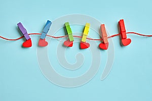 Rainbow colored wooden clothespins and red hearts on grey concrete background