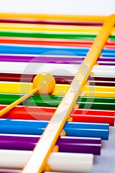 Rainbow colored wooden toy xylophone against white background