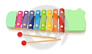 Rainbow colored wooden toy xylophone isolated on white background with shadow reflection. Colorful wooden metallophone toy