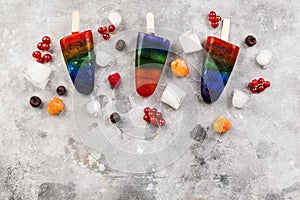 Rainbow colorful ice cream popsicle with wood stick on a gray background. Top view, copy space. Food background