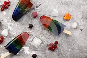 Rainbow colorful ice cream popsicle with wood stick on a gray background. Top view. Food background