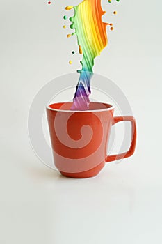 Rainbow of colors symbolizing creativity into a red cup with a white background