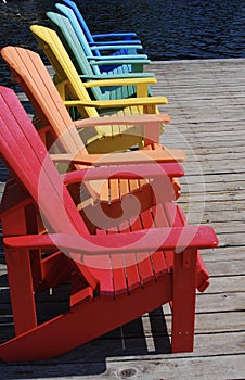 Rainbow of coloured chairs on the dock in summer