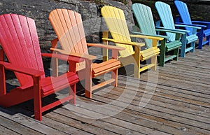 Rainbow of coloured chairs on the dock in summer