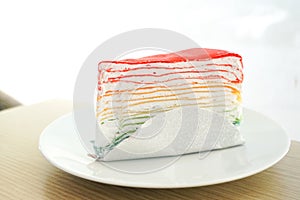 Rainbow crape cake on white plate on wooden table