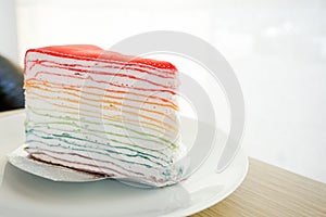 Rainbow crape cake on white plate on wooden table