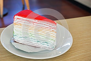 Rainbow crape cake on white plate on wooden table