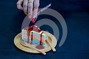 Rainbow crepe cake with strawberry jam on wooden plate