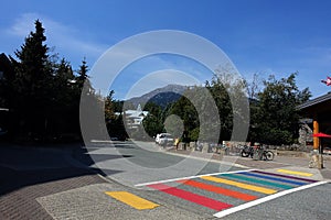A rainbow crosswalk on a street in mountain village.