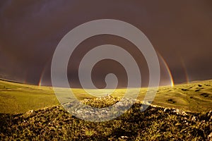 Rainbow with dark sky over a meadow
