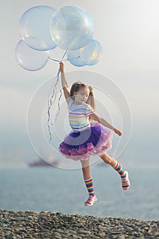 Rainbow dressed girl flying away on the bunch of soap bubbles