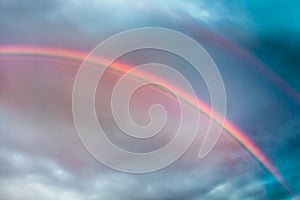 Rainbow echoes in the stormy skies. Thick rainbows curtain appeared after a storm followed with a secondary rainbow to the upper