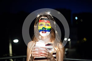 Rainbow face art on a young girl at night with bokeh
