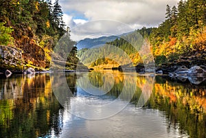 A rainbow of fall colors is reflected in the smooth Rogue River while white water rafting with some friends