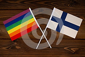 Rainbow flag LGBT and flag of Finland on beautiful brown background with wooden texture. LGBT Pride Month. LGBTQ. LGBTQIA. Human