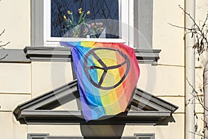Rainbow flag with peace sign hanging out of a window on the facade of a house