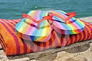 Rainbow flip-flops and towel on a dock