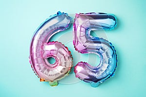 Rainbow foil balloon number, digit sixty-five. Birthday greeting card with inscription 65. Anniversary concept. Top view