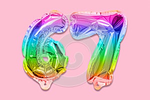Rainbow foil balloon number, digit sixty seven on a pink background. Birthday greeting card with inscription 67.